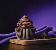 a chocolate cupcake sitting on top of a wooden tray