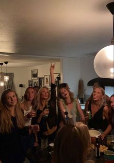 a group of women standing around each other in a room with one woman raising her hand