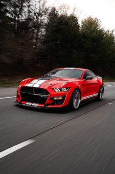 a red ford mustang driving down the road