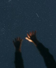 two hands reaching up at the stars in the sky