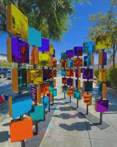 many colorful chairs are lined up on the sidewalk