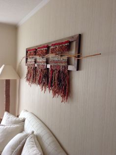 a wall hanging on the side of a bed next to a lamp and pillow case