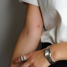 a woman's arm with a small triangle tattoo on the left side of her arm