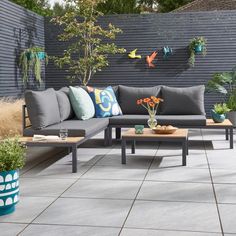 a couch and coffee table on a patio with potted plants in the back ground