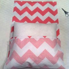 a pair of scissors sitting on top of a pink and white pillow with a chevron pattern