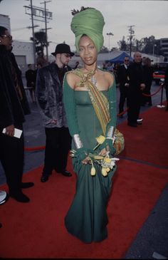 a woman in a green dress and headdress on the red carpet at an event