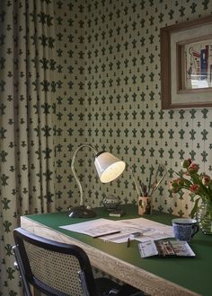 a green desk with a lamp on it and some papers sitting on top of it