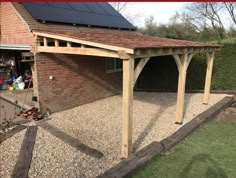 a wooden structure with solar panels on top and gravel in the ground next to it