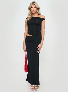 a woman wearing a black dress with one shoulder cut out and a red handbag