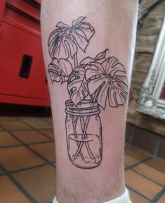 a black and white photo of a plant in a glass jar on the leg,