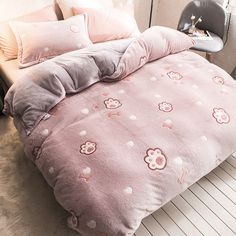 a bed with pink and grey comforters on top of it next to a window