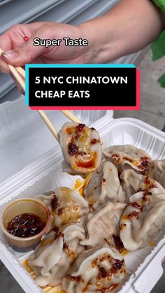 a person holding chopsticks over some dumplings in a plastic container with sauce