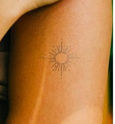 a woman's arm with a small sun tattoo on the back of her leg