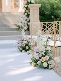 an outdoor ceremony set up with white and pink flowers, greenery and gold chairs