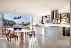 an open kitchen and dining area with large windows overlooking the ocean is pictured in this image