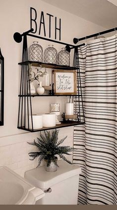 a bathroom with black and white decor on the shelf above the toilet is decorated with greenery