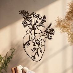 a metal heart with flowers and leaves hanging on the wall next to a planter