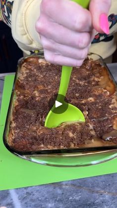 a person scooping some food out of a pan with a green spatula on it