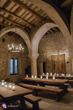 candles are lit in the middle of a room with stone walls and vaulted ceilinging