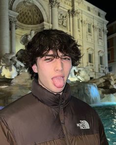 a man sticking his tongue out in front of a fountain