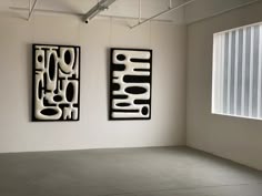 two black and white paintings hanging on the wall next to each other in an empty room