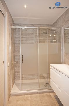 a bathroom with a walk in shower next to a white sink and counter top under a mirror