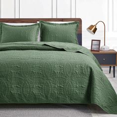 a bed with green bedspread and pillows