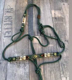 a horse bridle on a wooden floor with green rope and beads around it