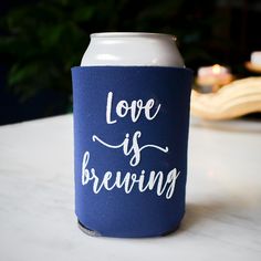 a can cooler with the words love is brewing on it sitting on a white table