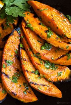 grilled sweet potato wedges with cilantro and lime on a black plate