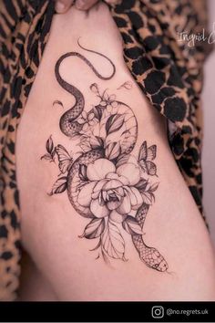 a woman with a snake and flowers tattoo on her thigh