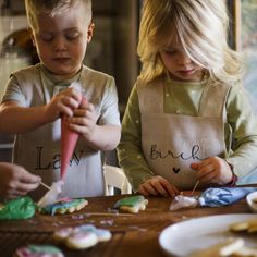 two young children making cookies on a table