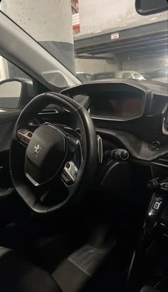 the interior of a small car with black leather seats and steering wheel, in a parking garage