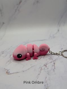 a pink keychain shaped like a gerbil laying on top of a marble counter