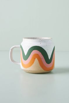 a coffee cup with an orange, green, and white design on the inside is sitting on a table