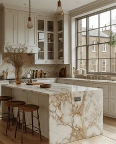 a kitchen with marble counter tops and stools in front of an open - air window