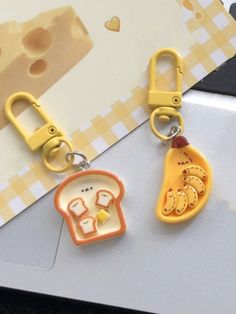 two keychains with food shaped like slices of bread on top of a table