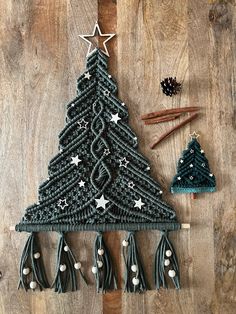 a crocheted christmas tree with tassels and other decorations on a wooden surface