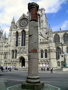 a tall building with a clock on it's side and people walking around in the background