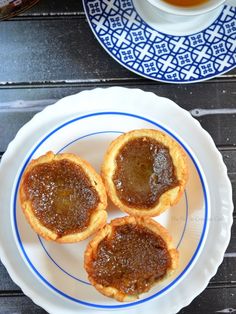 three small pastries on a plate next to a cup of tea