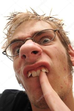 a man with glasses is holding his finger to his mouth