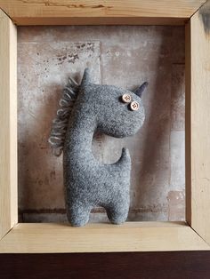 a gray stuffed animal in a wooden frame