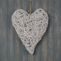 a white heart hanging on the side of a wooden wall with string attached to it