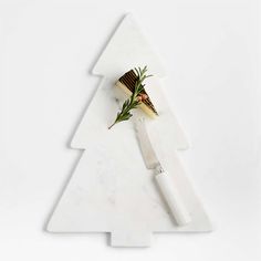 a white christmas tree shaped cutting board with cheese and herbs on it, next to a knife