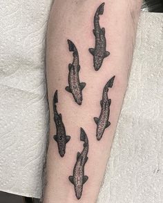 a person with a tattoo on their arm that has five black fish in the middle