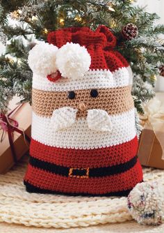 a crocheted santa claus bag sitting in front of a christmas tree