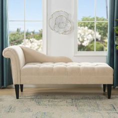 a white couch sitting in front of a window next to a rug and potted plant