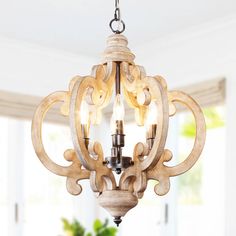 a wooden chandelier hanging from a ceiling in a room with white walls and windows