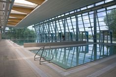 an indoor swimming pool with glass walls and stairs