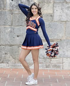 a woman in a cheerleader uniform holding a pom - pom and posing for the camera